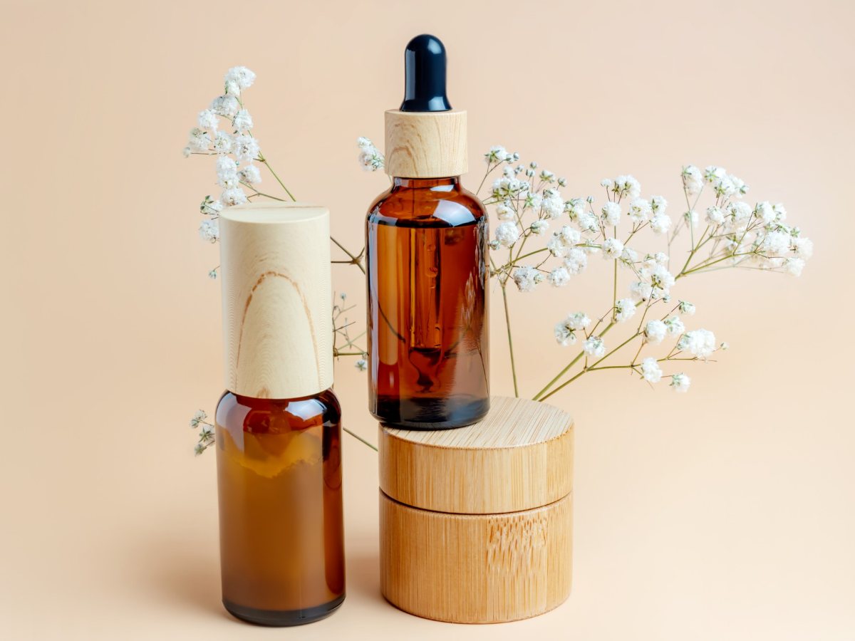 Amber glass dropper bottles and a bamboo jar beside white flowers