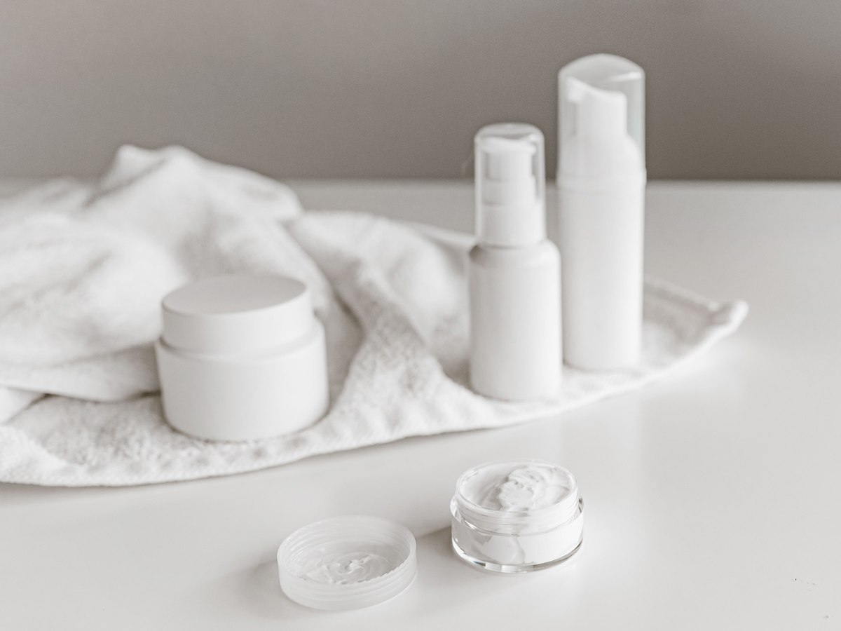 Plain white skincare bottles and jars on a light surface