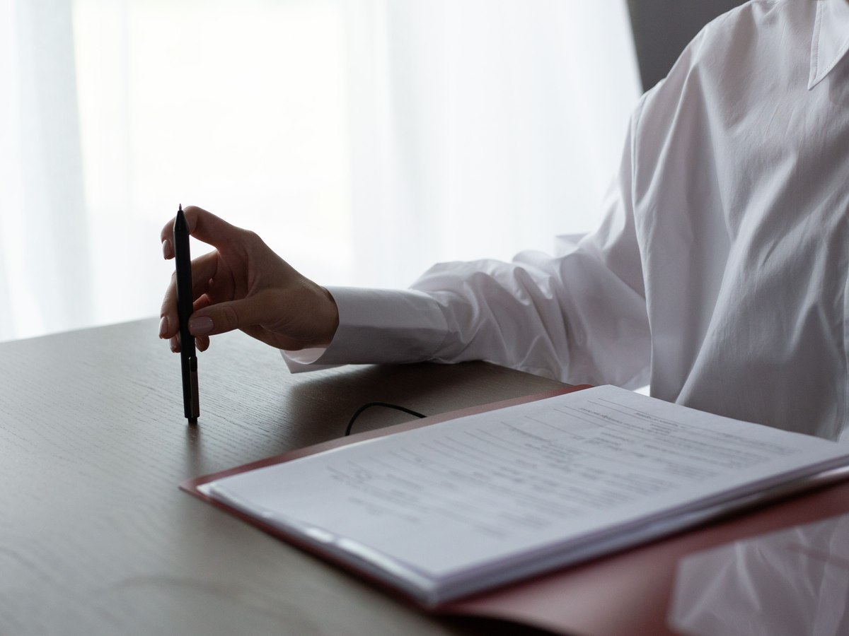 Hands reviewing a printed document with a pen at a desk